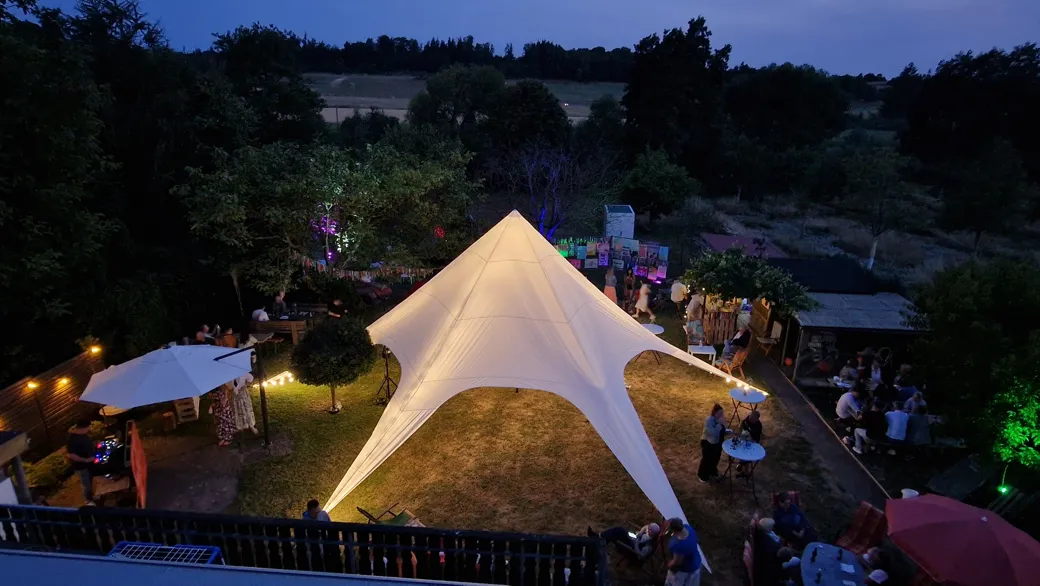 Sternenzelt 14×14 m aus der Vogelperspektive – beleuchtet bei einer Gartenparty am Abend
